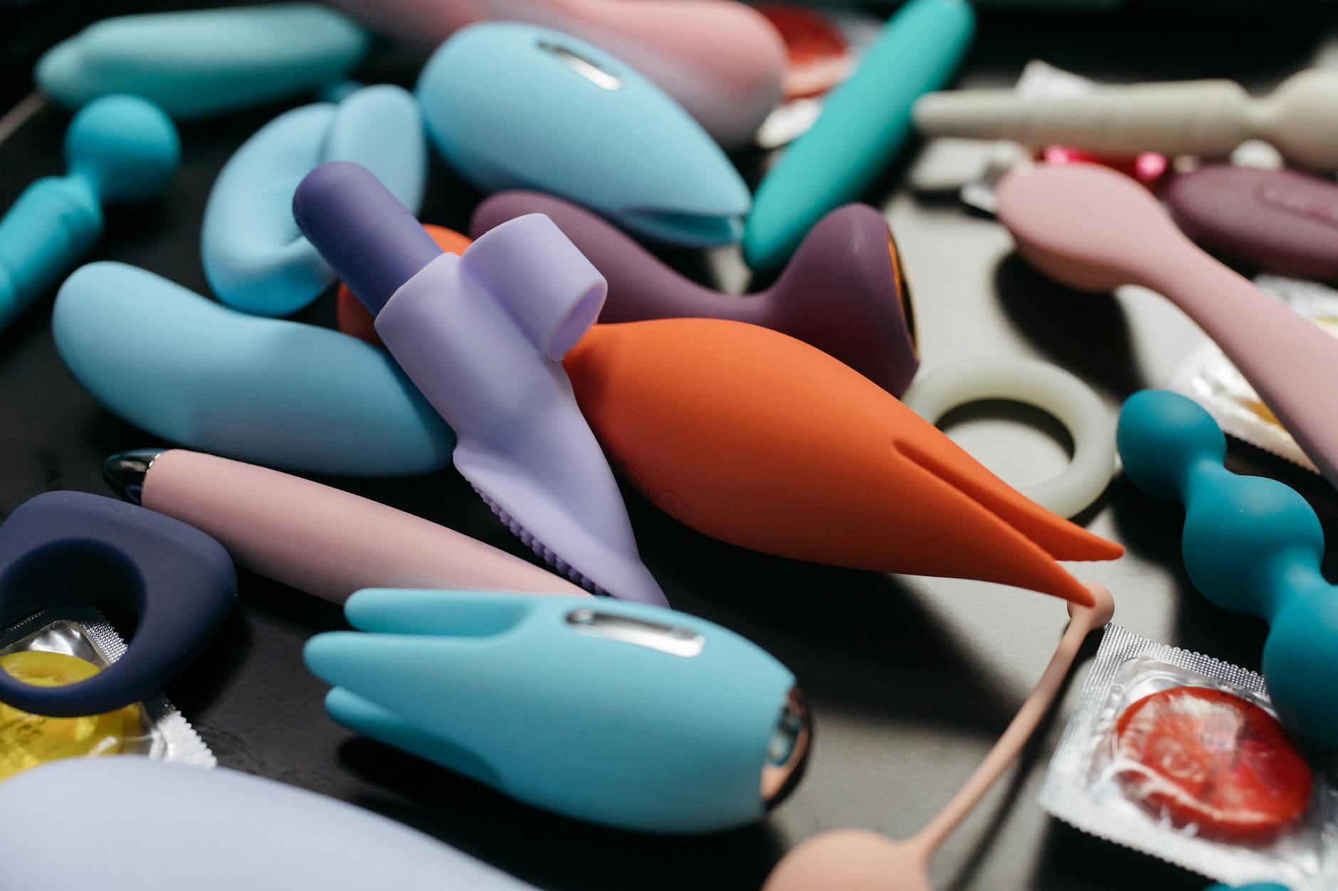 An array of colorful adult toys including vibrators displayed on a neutral surface