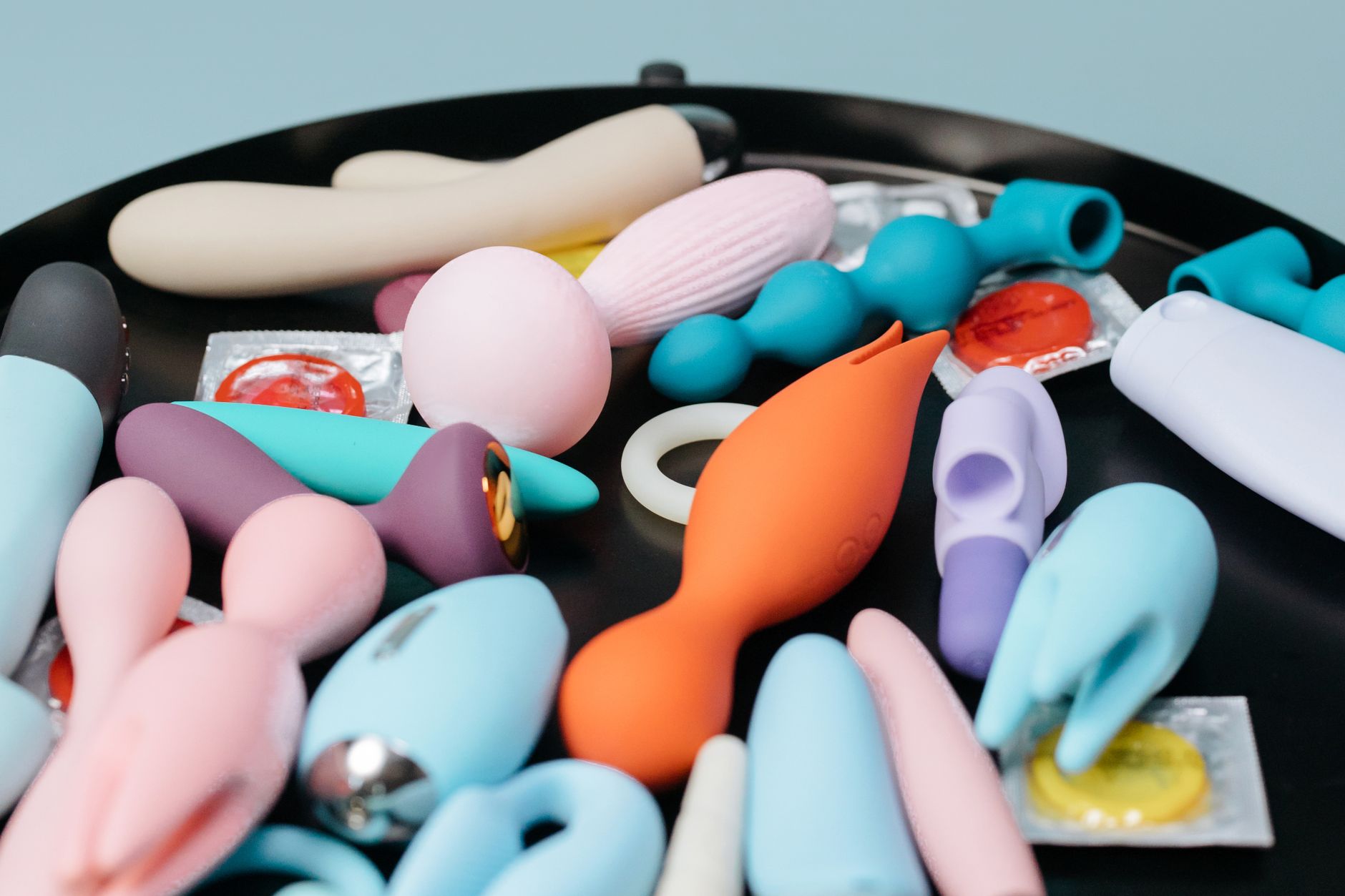 A collection of colorful sex toys on a black surface, representing diverse tools for intimate reconnection