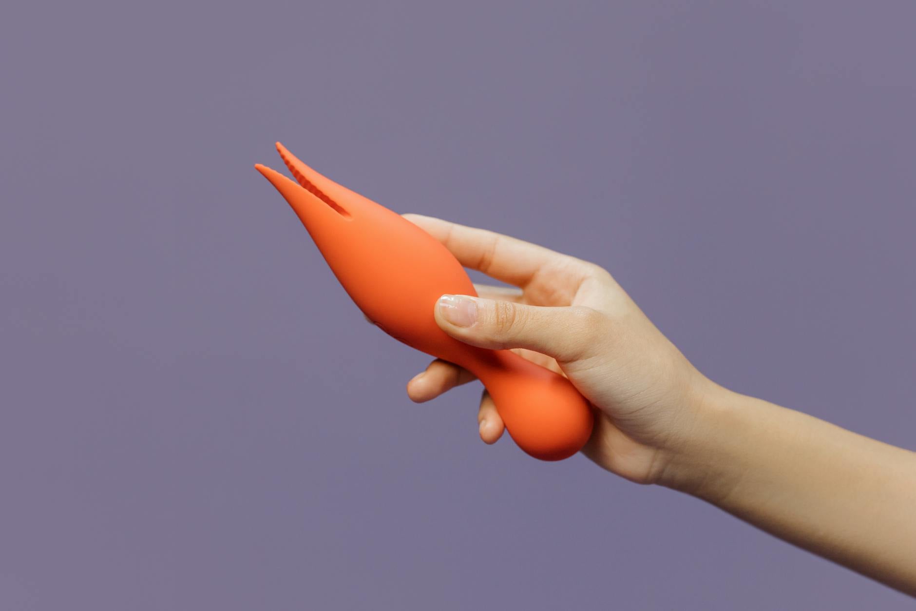 Hand holding a lemon vibrator against a minimalist purple backdrop, representing pleasure and sensuality