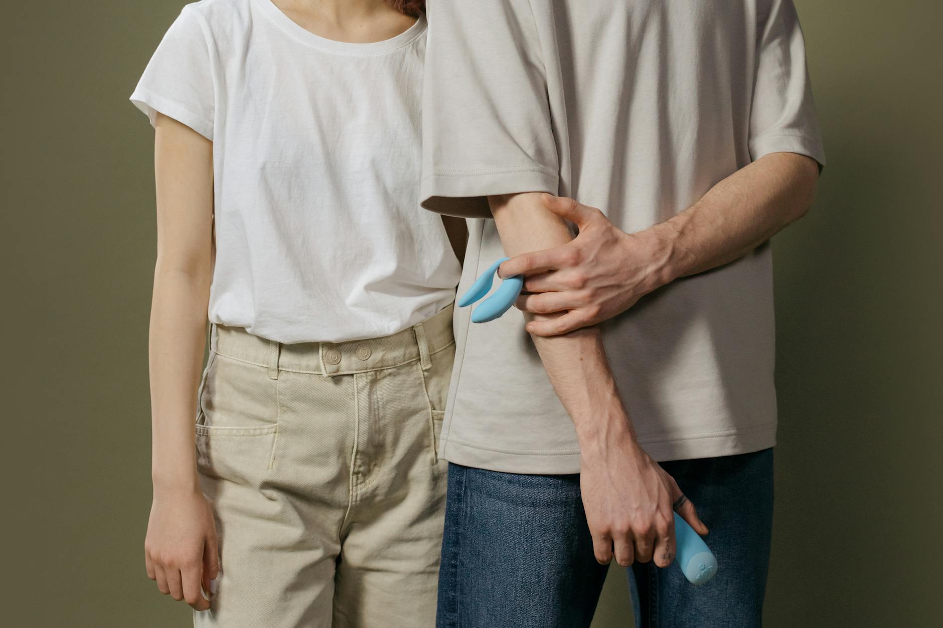 A couple standing together indoors holding a vibrator, symbol of modern intimacy and shared exploration